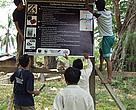 COMFISH staff work with villagers from Ban Muong Muan to nail down a sign board explaining village regulations.
