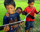 Three Khmer boys reading fish conservation book. On the banks of the Tonle Sap River, Cambodia.