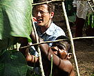 Man and woman building a thatched hut in the jungle.