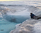 Researchers on safety ropes edge towards a cascade pouring into a newly opened crack on the Greenland ice sheet.