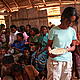 Henintsoa presenting 'Gena Gena,' a nutritionally complete cake, to a packed schoolhouse in Ambohitsara. © Christa Szumski