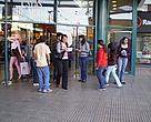 Voluntarios en la puerta principal del shopping entregando materiales.