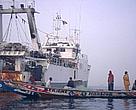 Artisanal pirogue with local fishermen passing Spanish trawler in their fishing grounds. Senegal. 