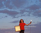 A young girl using solar energy through a photovaultic panel to power a lightbulb, Flagstaff, Arizona, United States.