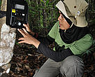 Lady sat checking a camera trap in the jungle