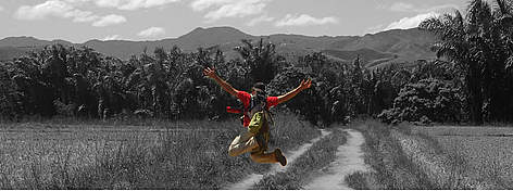 WWF Volunteer in Madagascar, October 2006 - jumping the air above a dirt track, with mountains and ... / ©: Julien Chupin rel=