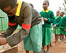 School girls filling water bottles at a water tap. Water is a threatened resource and with population growth and expanding urbanization the pressure can only increase. Protecting forests around water catchment areas is no longer a luxury but a necessity.  Nairobi City, Kenya