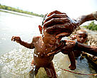 Bathing a young child in the April River, Pukapuki village. 